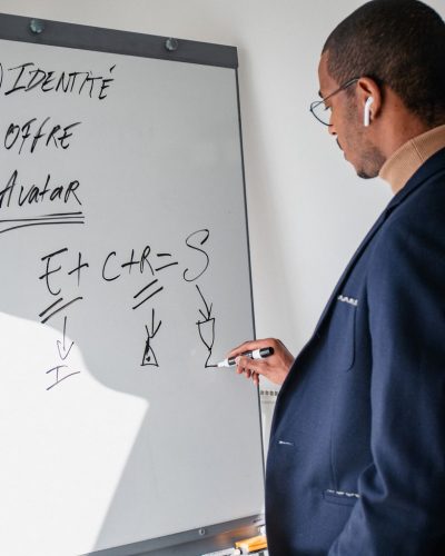 A man in a suit writes on a whiteboard, showcasing business ideas in a modern office setting.